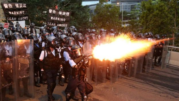 Police officers in Hong Kong fire tear gas at protesters.