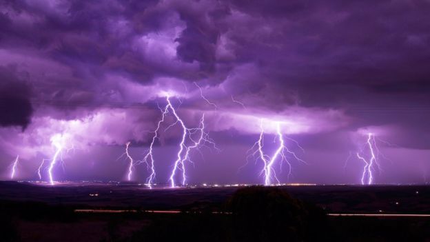 Photograph shows deep purple sky with flashes of several flashes of flightening