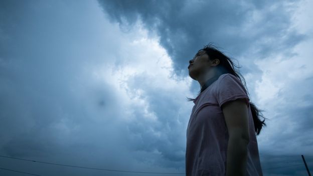 A woman looking up at storm clouds