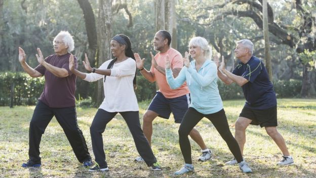 Adultos haciendo taichi al aire libre. Foto de kali9/ Getty Images.