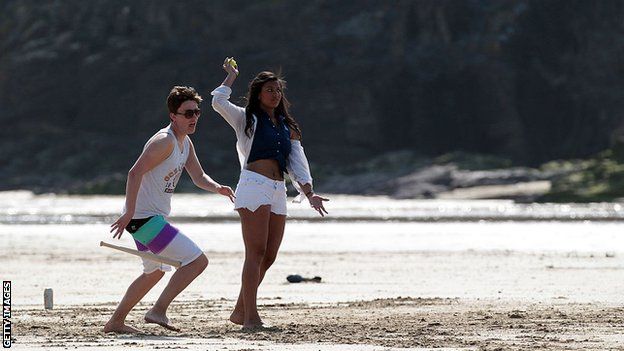 A couple play rounders on a beach in England