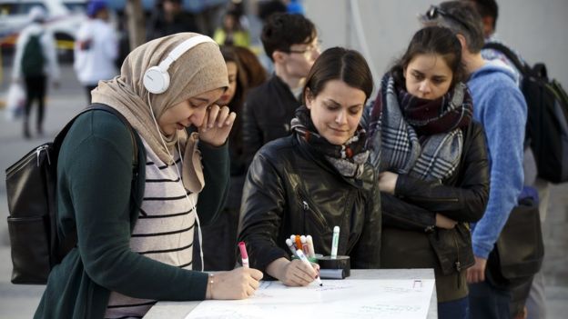 Three women signing, with one wiping tears away from her eyes