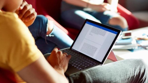 شاب يقرأ في جهاز كمبيوتر محمول