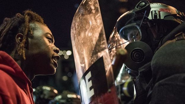 Un manifestante negro encara a un policía antidisturbios.