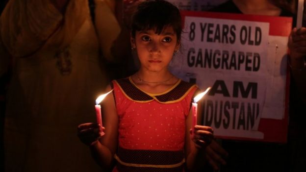 Uma menina indiana segura velas enquanto, junto com seus pais, participa de uma marcha à luz de velas para protestar contra o estupro e assassinato de uma menina de oito anos em Kathua, em Amritsar, Índia, 15 de abril de 2018