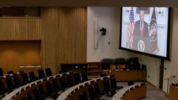 Donald Trump appears on a video screen to an empty conference room