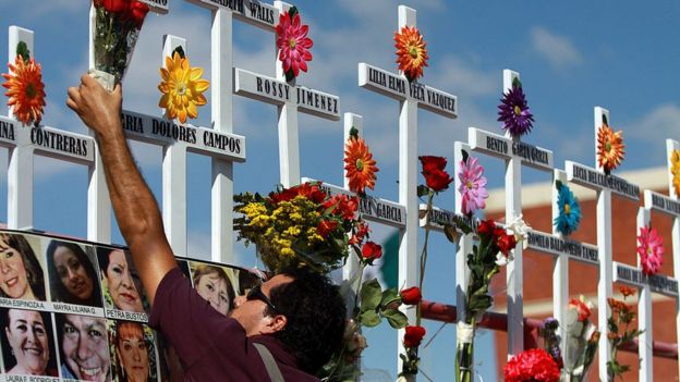 Un pariente de las víctimas del Casino Royale coloca flores en una cruz durante la conmemoración del primer aniversario del crimen en Monterrey, México, el 25 de agosto de 2012. 52 personas murieron el 25 de agosto de 2011, cuando miembros del cartel de drogas Los Zetas roció el Casino Royale con gasolina y lo incendió.
