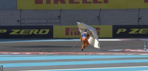 A marshal retrieves a giant parasol which appeared on the circuit