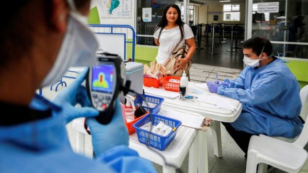 Personal de salud tomando la temperatura de una viajera en la frontera de Ecuador con Perú.
