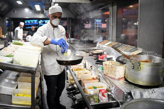 Os funcionários da cozinha do restaurante Kebabish Grill, em Glasgow, usam máscaras enquanto preparam a comida.