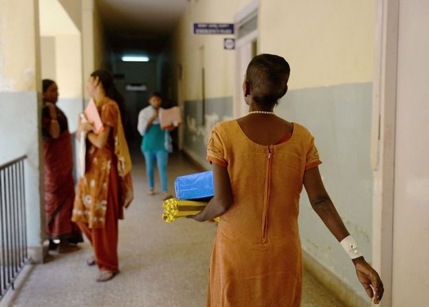 An Indian woman cancer patient (R) carries a box containing a hair wig donated by a health care company after an event as part of International Women's Day celebrations at Kidwai Cancer Institute in Bangalore on March 7, 2015. Hair-loss is one of the many side-effects of chemotherapy, which results in a loss of self-esteem in cancer patients and the gesture of donating them wigs was to boost their morale.