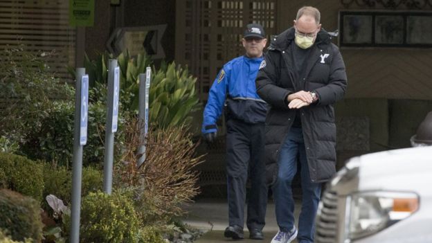 Two men emerge from a nursing home, one in official uniform and the other washing his hands, that reported several cases of coronavirus in Washington State.