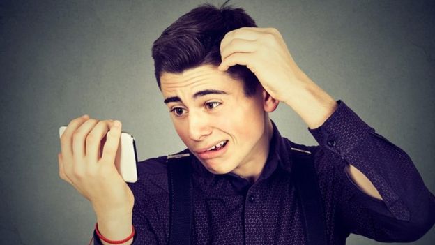 Un joven mira, confuso, su teléfono