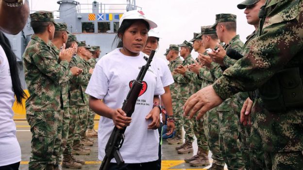 Una integrante del ELN entrega su arma al comandante general de las Fuerzas Militares, Juan Pablo Rodríguez Barragan, en Buenaventura, Colombia.