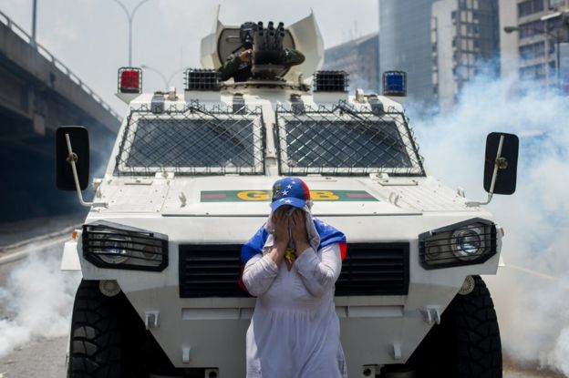 Mulher desconhecida fica em frente a tanque em Caracas