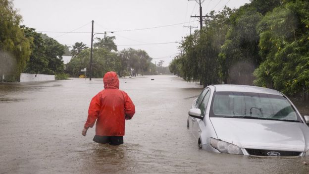 A man wades through flood water up to his thighs in Townsville