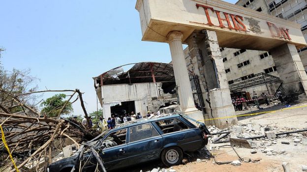 A car destroyed by the bomb sits outside the premises of ThisDay