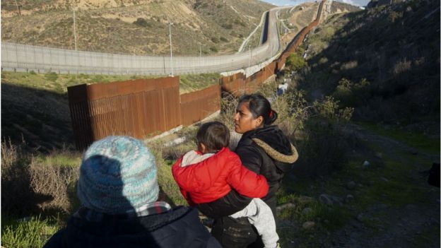 Honduran migrants walk toward the U.S.-Mexico border fence to cross over in Tijuana, Mexico