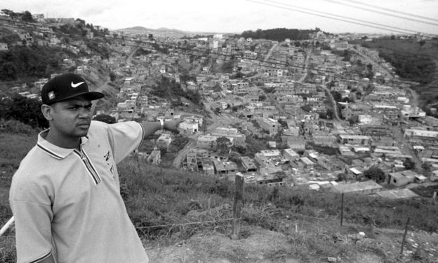 Edi Rock aponta para o Capão Redondo, bairro da periferia de São Paulo onde surgiram os Racionais.