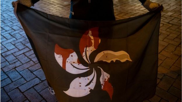 A protester holds a black flag with the Hong Kong emblem in blood at a vigil to commemorate a protester who died 11 months ago during a rally against the controversial extradition law proposal in Hong Kong
