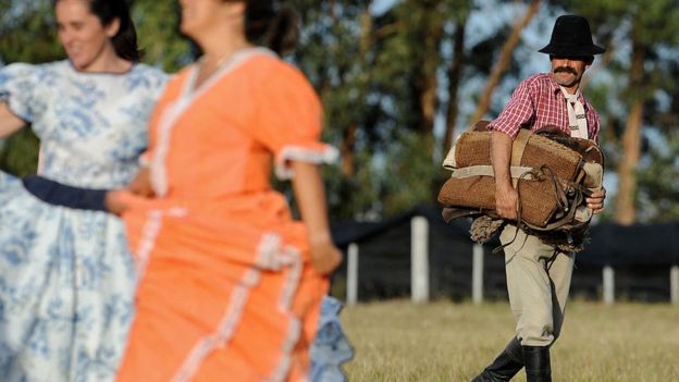 Un hombre de campo uruguayo mira a dos mujeres bailar.