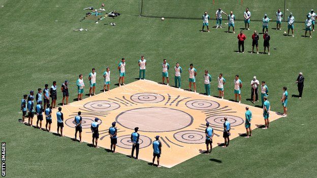 Australia and India players stand around an aboriginal symbol while barefoot in a stand against racism and acknowledgement of indigenous Australia before the first ODI