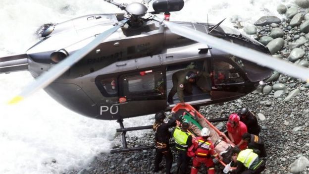 A group of emergency personnel load a victim onto a helicopter which has landed on a rocky shoreline, during rescue operations after a bus plunged off the Pan-American Highway North, about 45 kilometers from Lima, Peru, 02 January 2018 (handout photo made available by Agencia Andina)