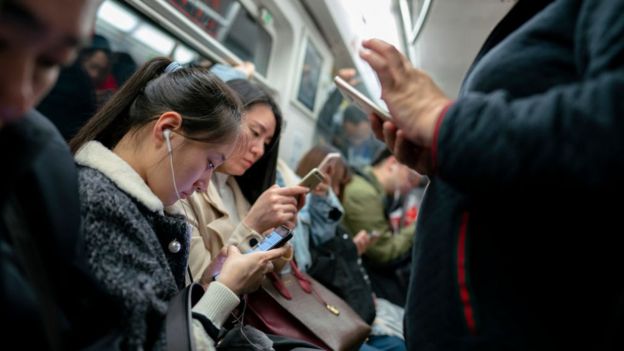 Personas en el metro con teléfonos en la mano.