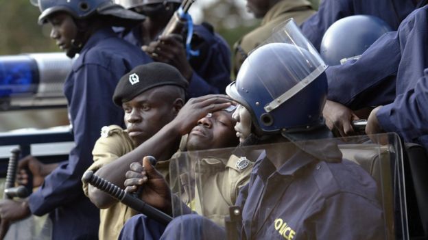 Polisi akipoozwa na mwenzake baada ya kujeruhiwa na waandamanaji mjini Kampala , Uganda