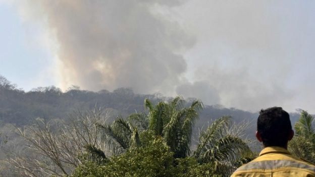 Un hombre mira el humo de un incendio en Bolivia.