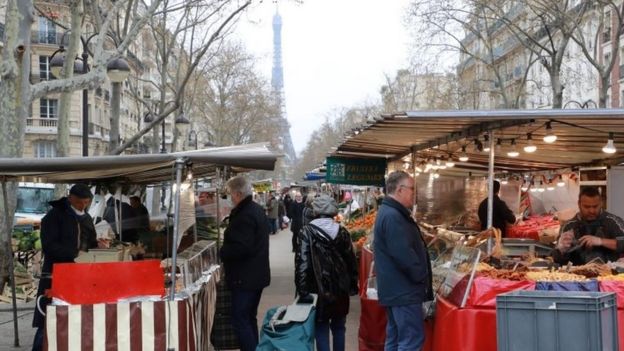 People shop at an open air market in Paris on March 21, 2020