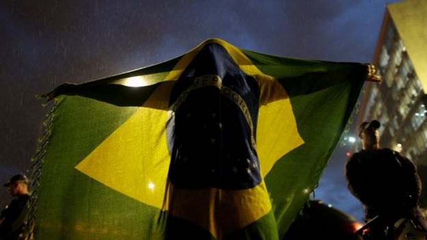 Manifestante em Brasília se cobre com a bandeira do Brasil