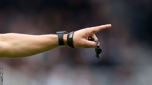 A referee's hand and whistle