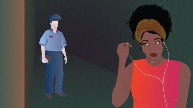 Woman lifting headphones as she is followed by a police officer