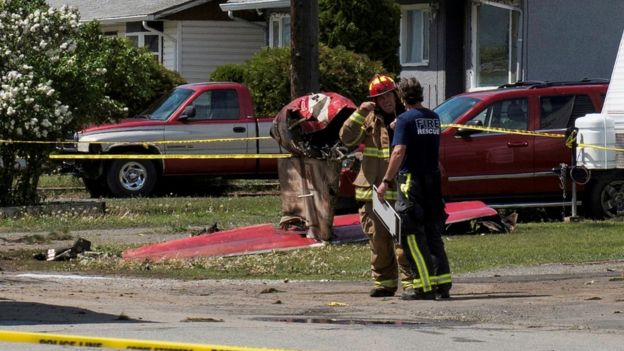 Fire officials talk in a residential neighbourhood street in front of the tail wreckage