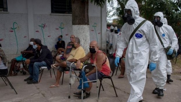 Brazilian soldiers in protective suits prepare to disinfect a public shelter in Rio de Janeiro. Photo: May 2020
