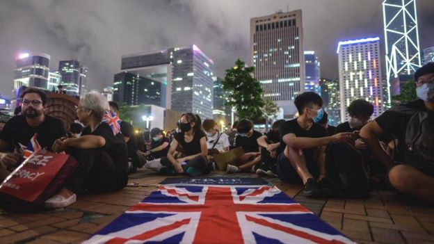 A British Union Jack flag is displayed as protesters gather along a fenced-off Victoria Harbour pier in Hong Kong
