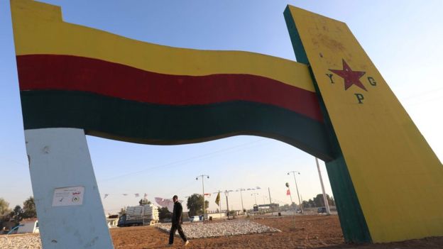 A Syrian man walks next to a monument painted with the YPG flag in the north-eastern city of Qamishli (30 November 2017)