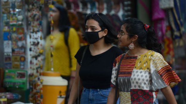 இந்தியத் தலைநகர் டெல்லியில் கொரோனா வைரஸ் தொற்றுக்கு பயந்து முகக் கவசம் அணிந்து கடைத்தெருவில் நடக்கும் பெண்கள்.