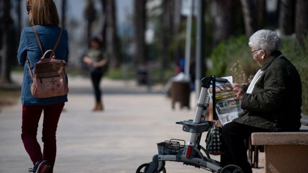 Una mujer de la tercera edad leyendo el periódico en un parque.