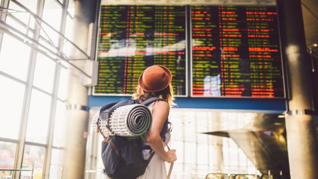 Viajera mirando la información sobre las llegadas y salidas de vuelos en un aeropuerto.