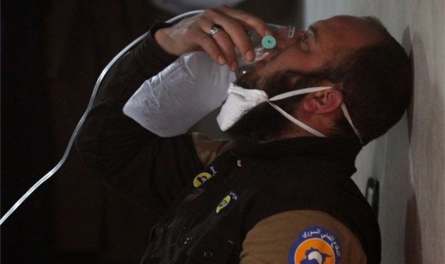 A rescuer breathes through an oxygen mask after the attack on Khan Sheikhoun