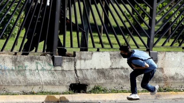 Un miembro de las fuerzas de seguridad antidisturbios apunta un arma a través de la reja de una base de la fuerza aérea contra David José Vallenilla, quien resultó fatalmente herido durante una manifestación contra el gobierno del presidente venezolano, Nicolás Mauro, en Caracas, Venezuela, el 22 de junio de 2017.