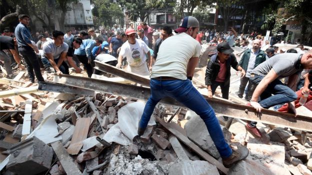 People remove debris of a building which collapsed after a quake rattled Mexico City