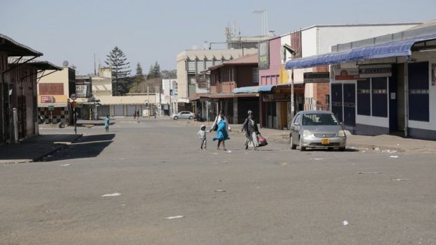 Women and a child walk on an deserted street and closed shops, a day before anti government protests, in the central business district of Harare, Zimbabwe, 30 July 2020.