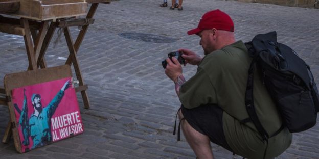 A tourist takes a picture of a painting in Havana
