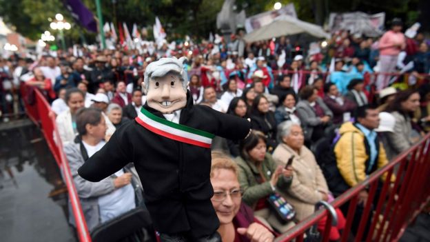 Boneco representando López Obrador, segurado por uma apoiadora do candidato em um comício no México