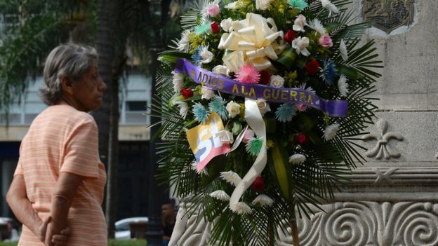 Una corona de flores con el mensaje adiós a la guerra.
