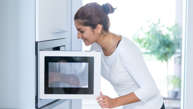 Mujer cocinando al microondas
