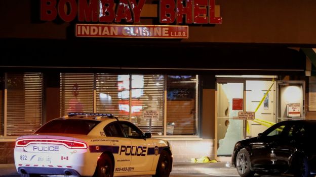 A police car is parked in front of shattered glass at the Bombay Bhel restaurant